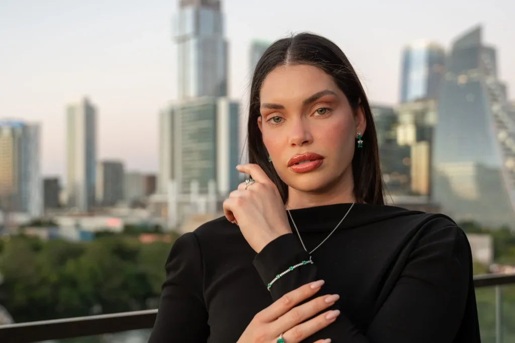 Model wearing an emerald pendant, emerald ring and tennis bracelet on an Austin rooftop, Eterna Jewels
