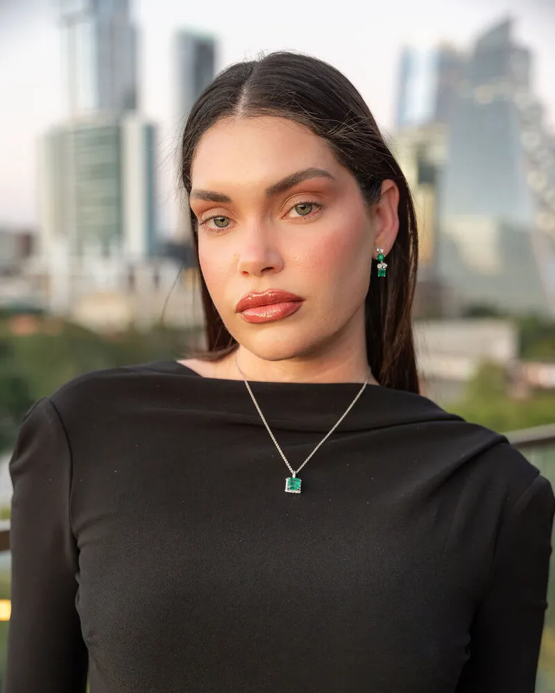 Model wearing an emerald pendant necklace and emerald earrings, Eterna Jewels Austin