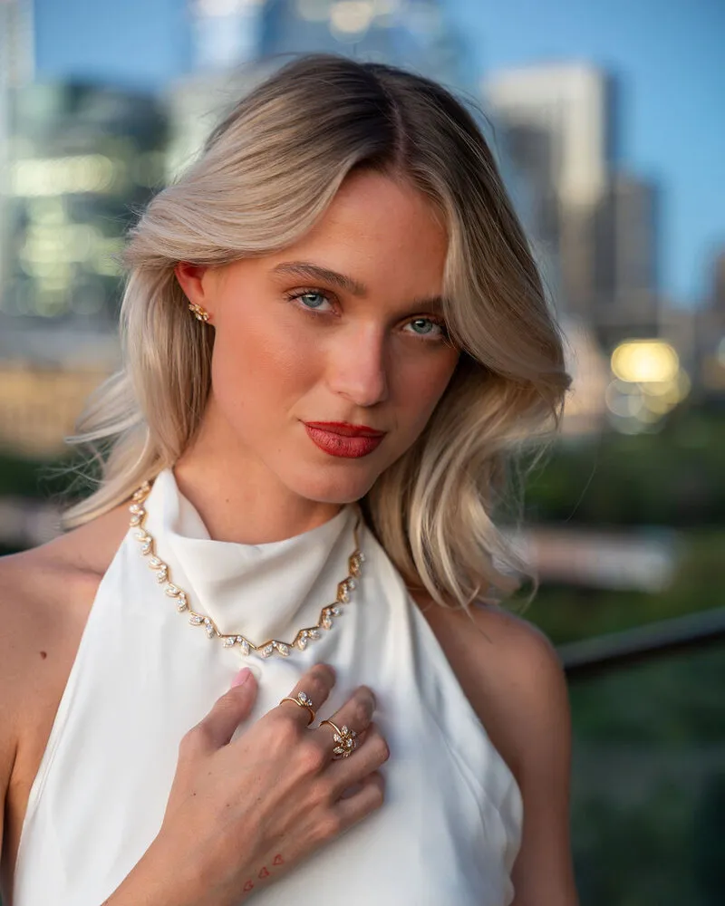 Model wearing a gold necklace with the Austin skyline behind her, Eterna Jewels