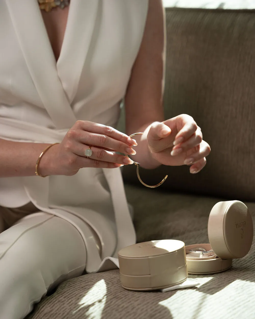 Hands holding a gold bracelet above Eterna Jewels jewelry boxes