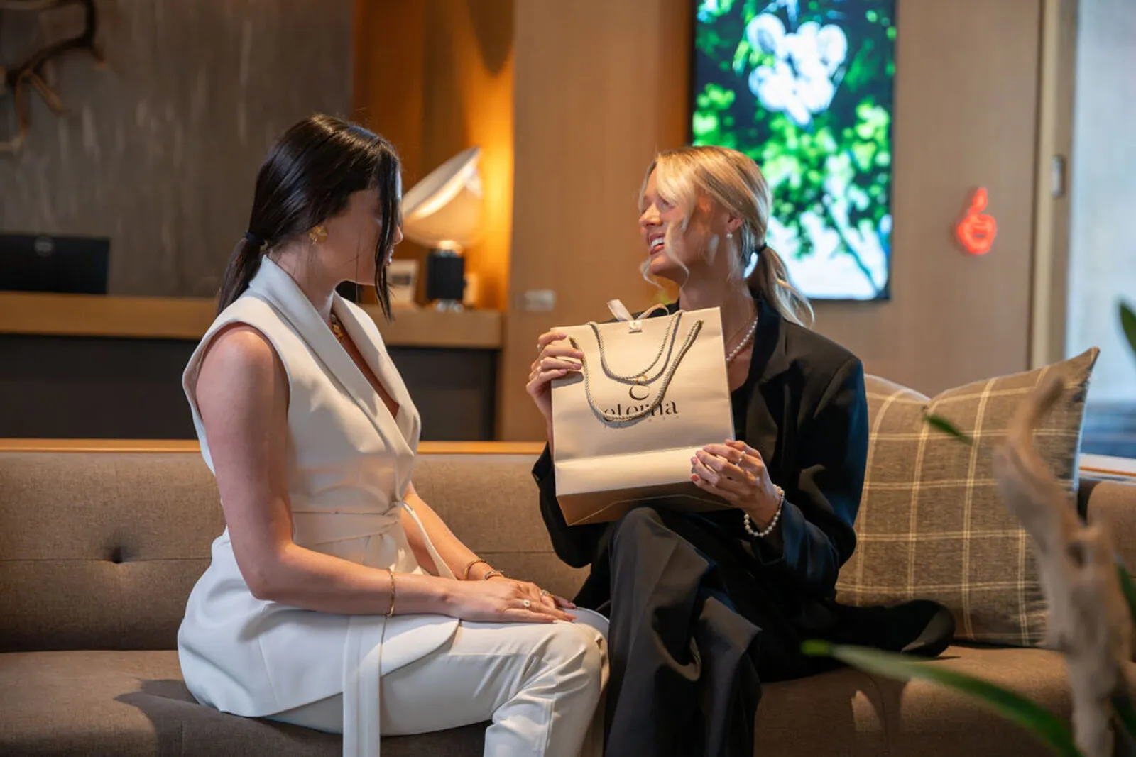 Two women opening an Eterna Jewels gift bag in an Austin hotel lounge