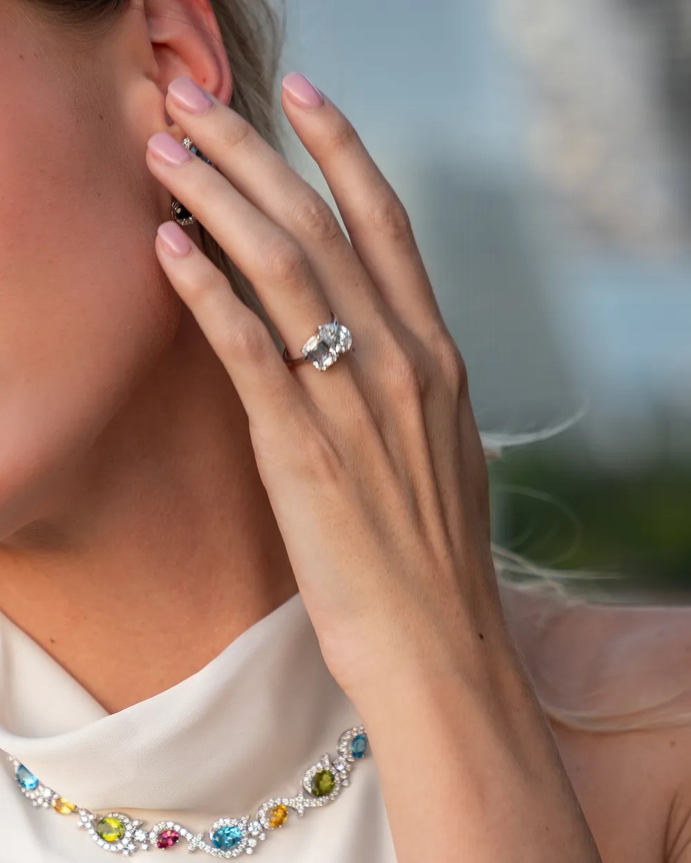 Diamond ring on a woman's hand held beside her face